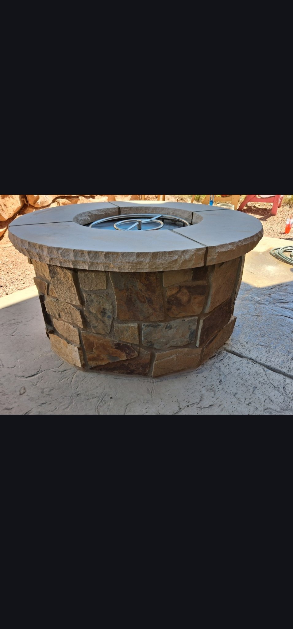 Round outdoor fire pit finished with stone veneer